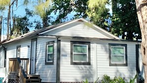 A single-story house with a front porch, a small staircase, and a fenced yard.