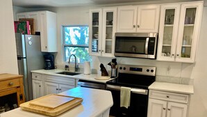 A modern kitchen with white cabinetry, a stainless steel refrigerator, a microwave, and an oven.
