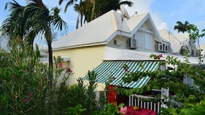 A house with a green-striped awning, a satellite dish, and a red table with a yellow item on it.
