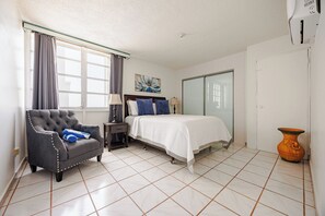Une chambre d  ’hôtel avec un lit, une chaise, une lampe, un vase et un tableau au mur.
