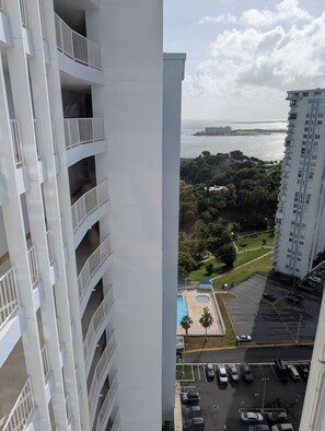 Un edificio de gran altura con varios balcones, un estacionamiento y vistas al mar.