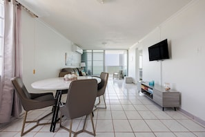 Uma cozinha moderna com área de refeições, uma TV na parede e vista para o exterior.