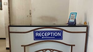 A reception desk with a sign indicating 'RECEPTION' and a PayTM payment terminal. - Hotel Sweet Dream (Rajkot)