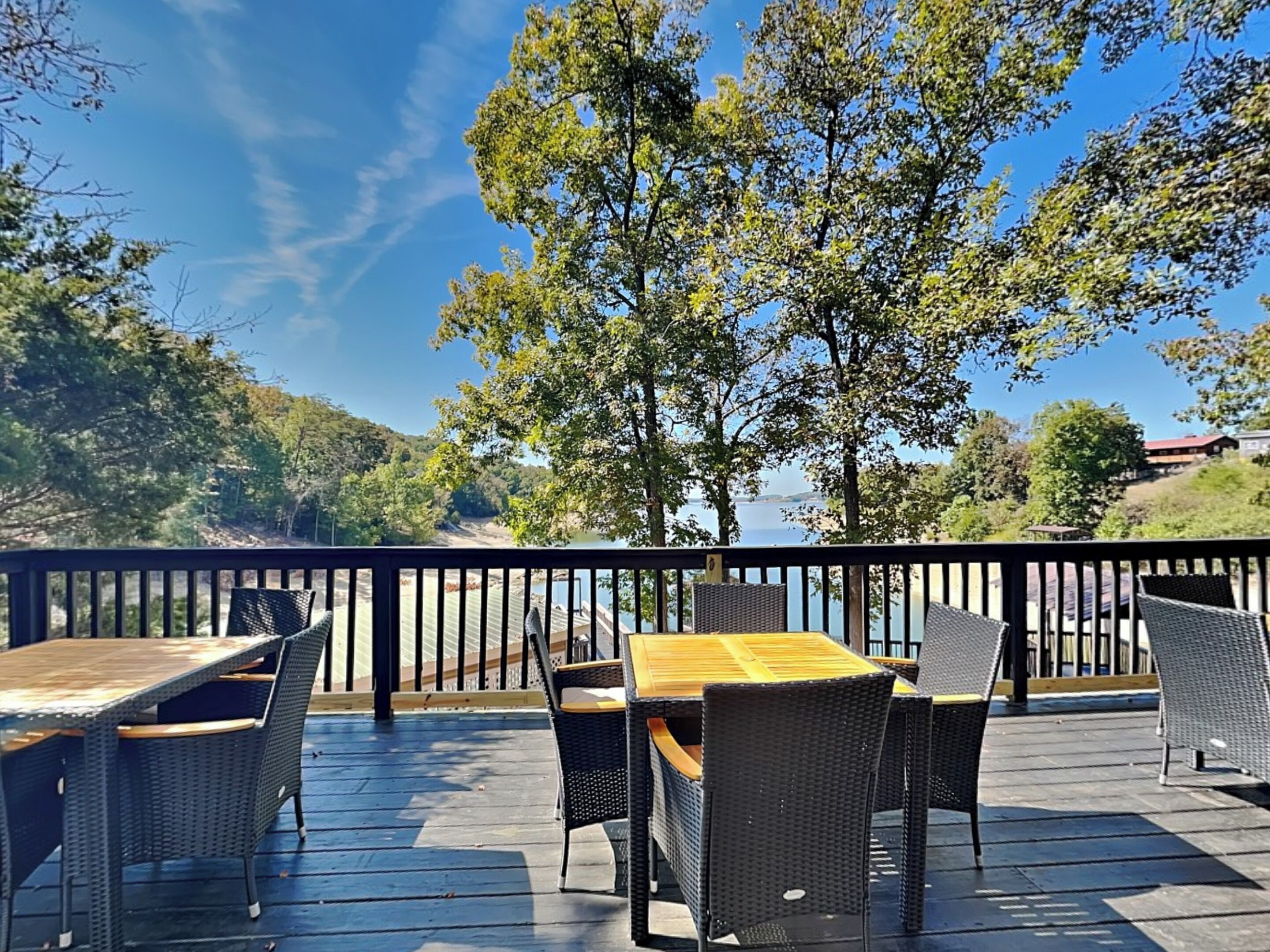 A deck with outdoor furniture and a view of a lake and hills.