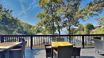 A deck with outdoor furniture and a view of a lake and hills.