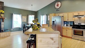 Een moderne keuken met houten kasten, roestvrijstalen apparatuur en een centraal eiland met barstoelen.