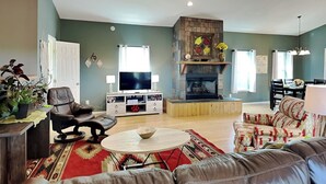 Een woonkamer met een open haard, leren banken, een televisie en een eethoek.