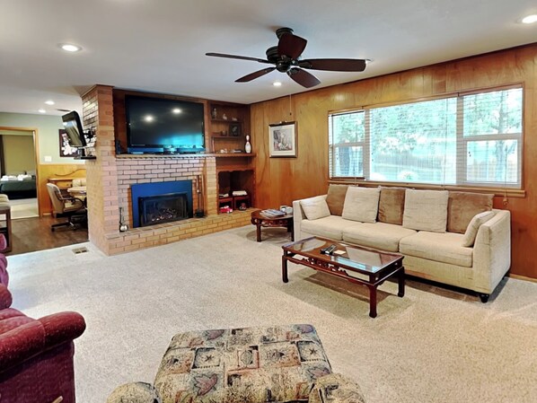 A living room with a fireplace, a sofa, a coffee table, and a television. - Brooksland (Ruidoso)
