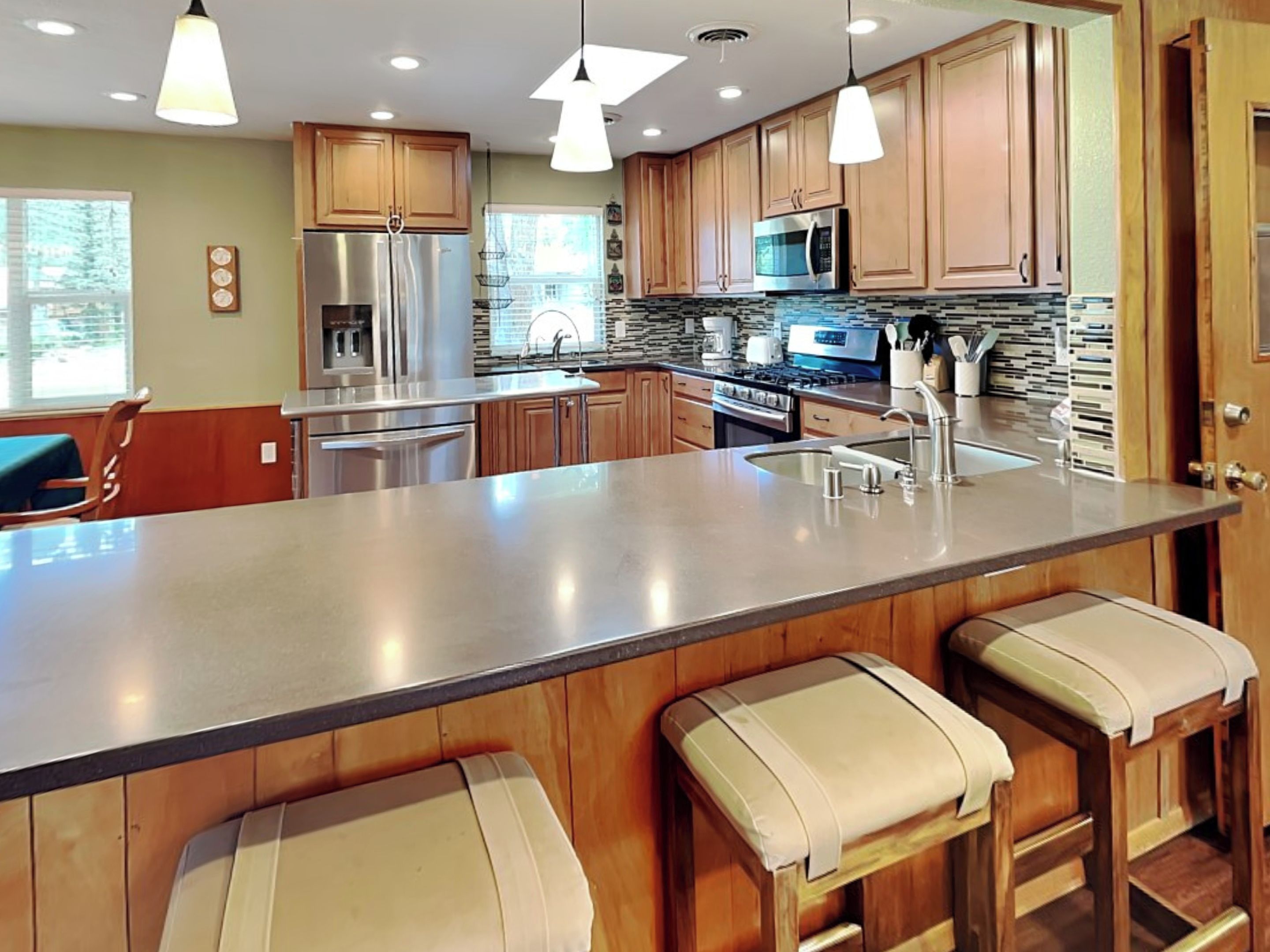 Una cocina moderna con electrodomésticos de acero inoxidable, armarios de madera y una isla grande con taburetes de bar.