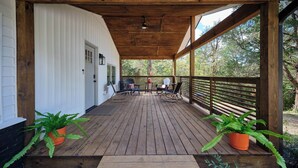 A wooden deck with outdoor seating, potted plants, and a view of trees.