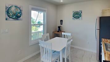 A kitchen with white cabinets, a black refrigerator, and a window with a view of greenery.