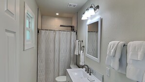 Une salle de bain avec des toilettes, un lavabo et un rideau de douche.
