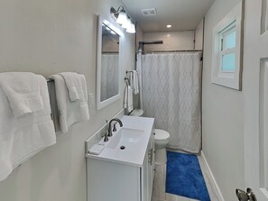 A bathroom with a white sink, a mirror, and a shower curtain. - Blue Marlin #11 (Rockport)