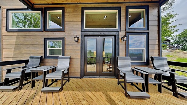 A wooden deck with outdoor seating and large windows. - Sunrise in the Cove (Sevierville)