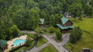 A lodge with a swimming pool, surrounded by dense forest and a mountain backdrop. - Sunrise in the Cove (Sevierville)