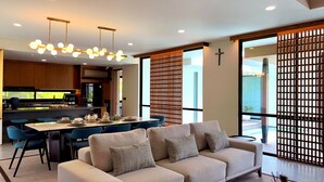 Ein modernes Wohnzimmer mit einer Couch, einem Esstisch mit Stühlen und einer Küche im Hintergrund.