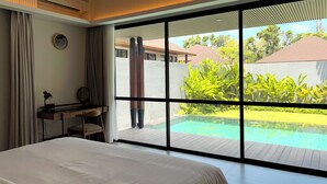 Ein modernes Hotelzimmer mit einem großen Bett, einem Schreibtisch und Blick auf einen Swimmingpool.