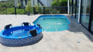 A swimming pool with a tiled edge and a hot tub, surrounded by a balcony with a railing.