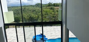 A view from a balcony with a swimming pool and a scenic landscape.