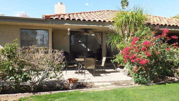 Una casa con patio, mobiliario exterior y una zona cubierta.