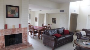 Un amplio espacio de estar con chimenea, sofás de cuero, una mesa de comedor y vistas al comedor contiguo.