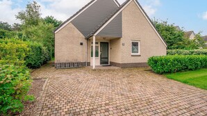 Ein zweistöckiges Haus mit Backsteinfassade, geneigtem Dach und befestigter Auffahrt.
