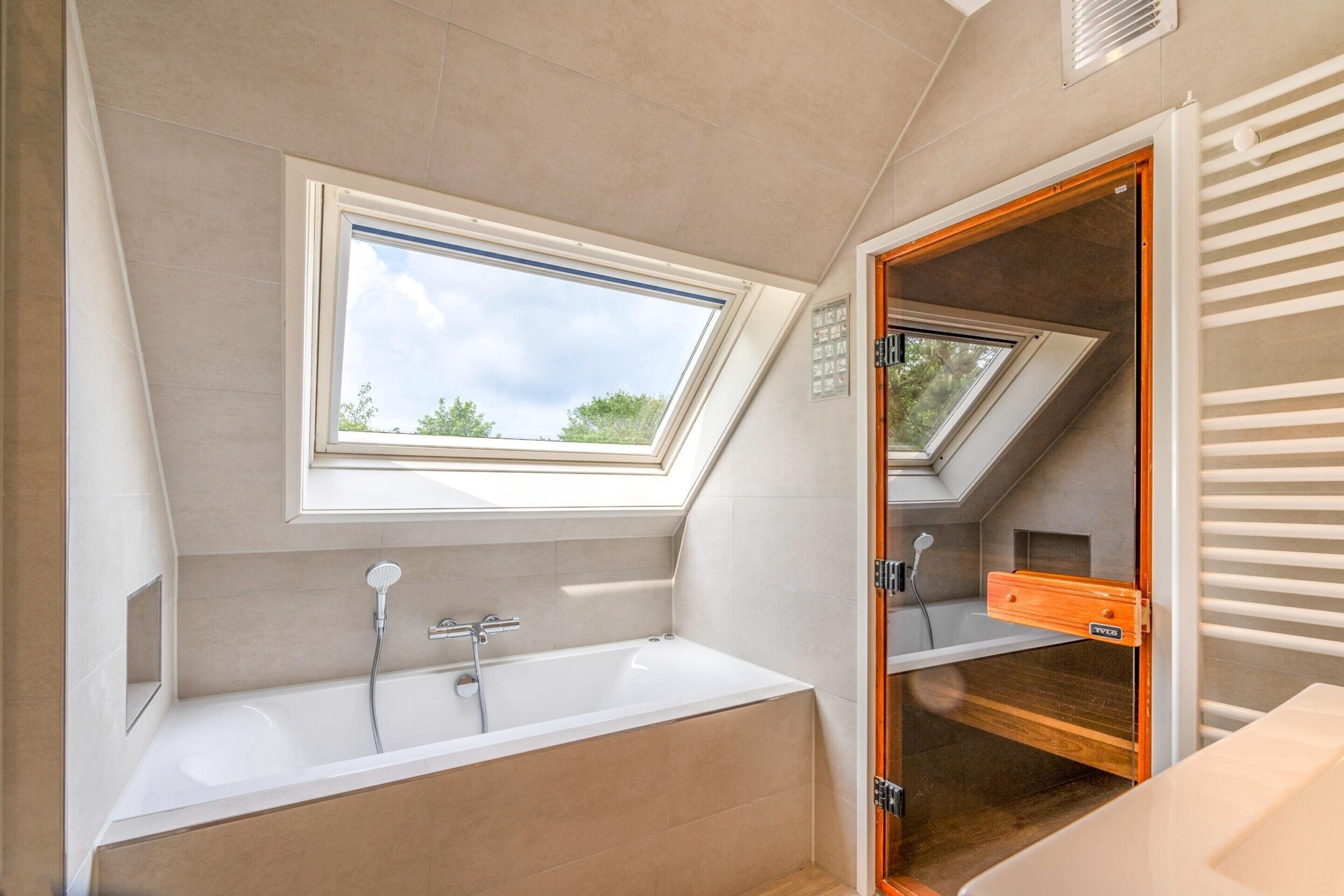 A modern bathroom with a skylight, a bathtub, and a shower.