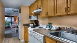 A kitchen with wooden cabinets, a microwave, a stove, and a sink. - 2BR Condo in Myrtle Beach w/ Kitchen + Pool Access (Myrtle Beach)