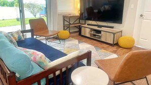Een woonkamer met een bank, stoelen, een televisie en een salontafel.