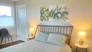Een slaapkamer met een groot bed, twee nachtkastjes met lampen, een stoel en een deur.