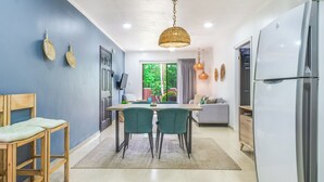 A modern kitchen with a dining table, chairs, and a hanging light fixture.