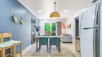A modern kitchen with a dining table, chairs, and a hanging light fixture.