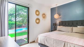 A bedroom with a large bed, a view of a swimming pool, and a sliding glass door.