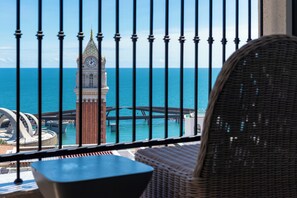 Ein Balkon mit Blick auf das Meer, einen Glockenturm und eine Brücke.
