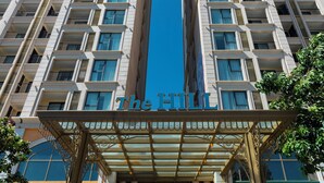 A high-rise hotel with a central entrance, multiple balconies, and a clear blue sky. - M Gallery Apartment Phu Quoc (Phu Quoc)