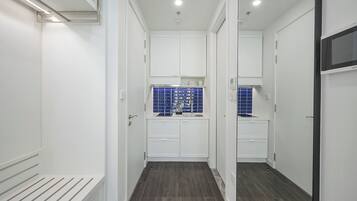 A narrow hallway with white cabinets and a blue tiled backsplash in the kitchen area.