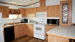 Una cocina con armarios de madera, una estufa blanca, un microondas y un lavavajillas.