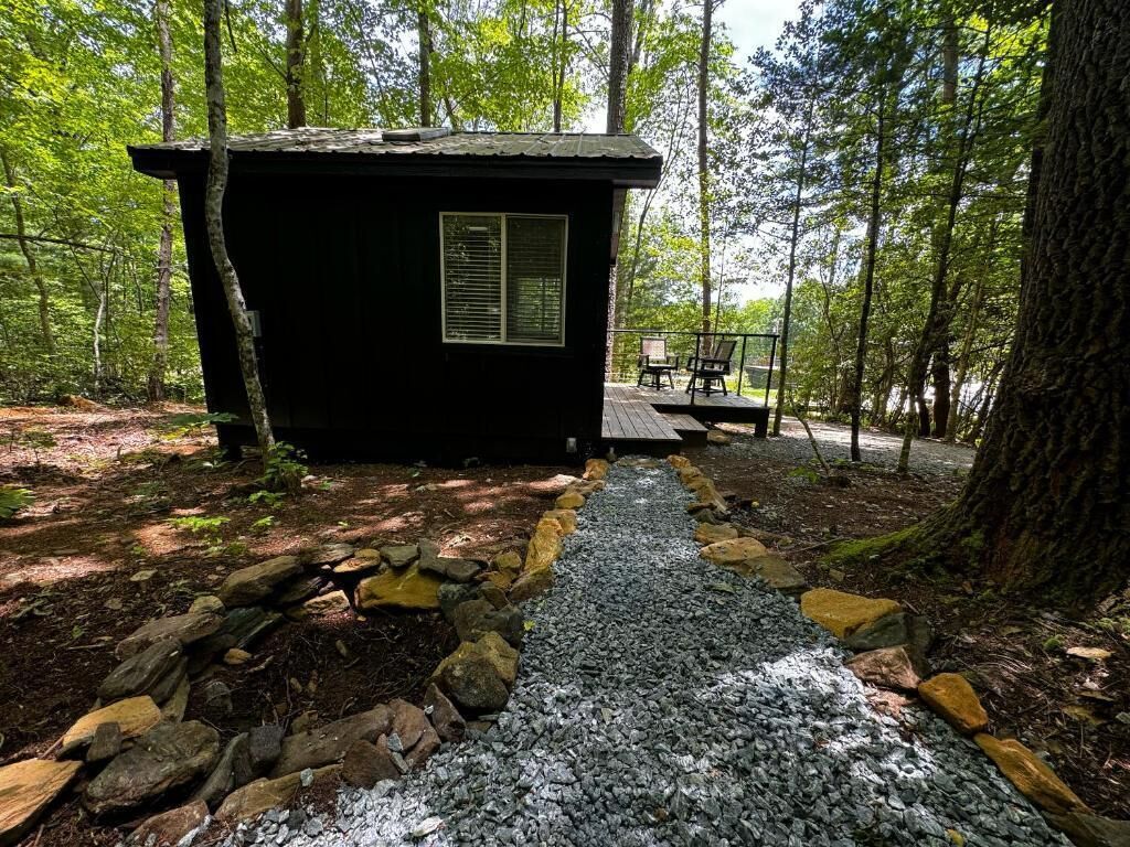 A small cabin with a gravel path leading to a deck.