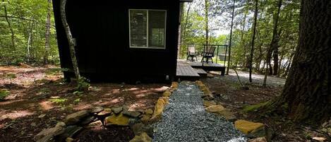 A small cabin with a gravel path leading to a deck.