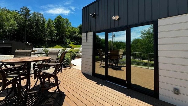 Un bâtiment moderne doté d’une terrasse, de sièges extérieurs et de grandes portes-fenêtres coulissantes.