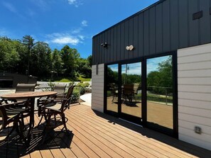Un bâtiment moderne doté d’une terrasse, de sièges extérieurs et de grandes portes-fenêtres coulissantes.
