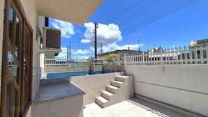 Zona residencial con piscina, una valla blanca y una escalera que lleva a un porche cubierto.