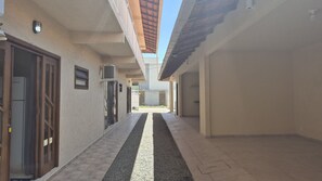A narrow corridor with a tiled floor, a central gravel path, and a door on the left. - Fully Equipped Houses in a Condominium With a Pool, 110m From the Beach - Onis (Barra Velha)