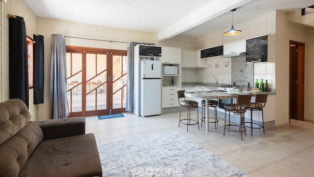 A modern kitchen with a central island, bar stools, and a dining area. - Fully Equipped Houses in a Condominium With a Pool, 110m From the Beach - Onis (Barra Velha)
