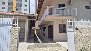 Un edificio residencial con entrada porticada, pasarela techada y balcón.