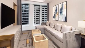 Ein modernes Wohnzimmer mit grauem Sofa, einem Flachbildfernseher und einem Couchtisch.
