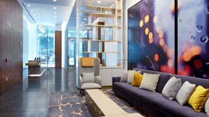 Eine moderne Lobby mit einer Couch, einem Sessel und einem großen abstrakten Gemälde.