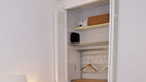 A hotel room with a neatly made bed, a bedside table with a lamp, and a walk-in closet with shelves and hanging space. - Modern 2-bedroom apartment in North Miami Beach with AC (North Miami Beach)