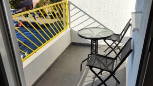 A balcony with a yellow railing, a small round table, and two chairs.