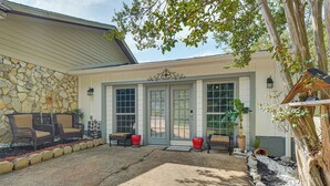 Ein Haus mit Steinaußenwand, einer Veranda mit Korbmöbeln und einem gepflegten Garten.